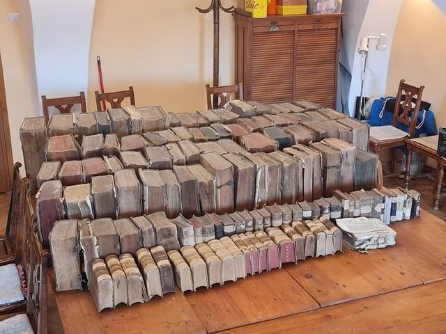 Tisch mit dicht gestapelten, gealterten Büchern in einem Wohnraum